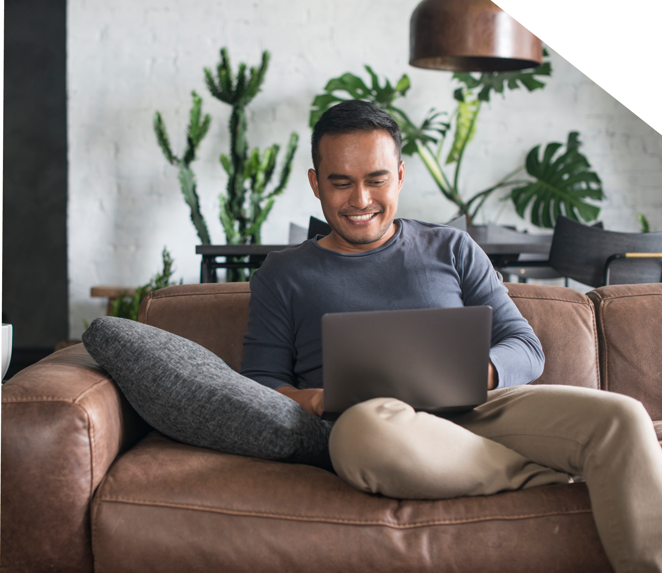 Man relaxing on couch with laptop browsing home listings