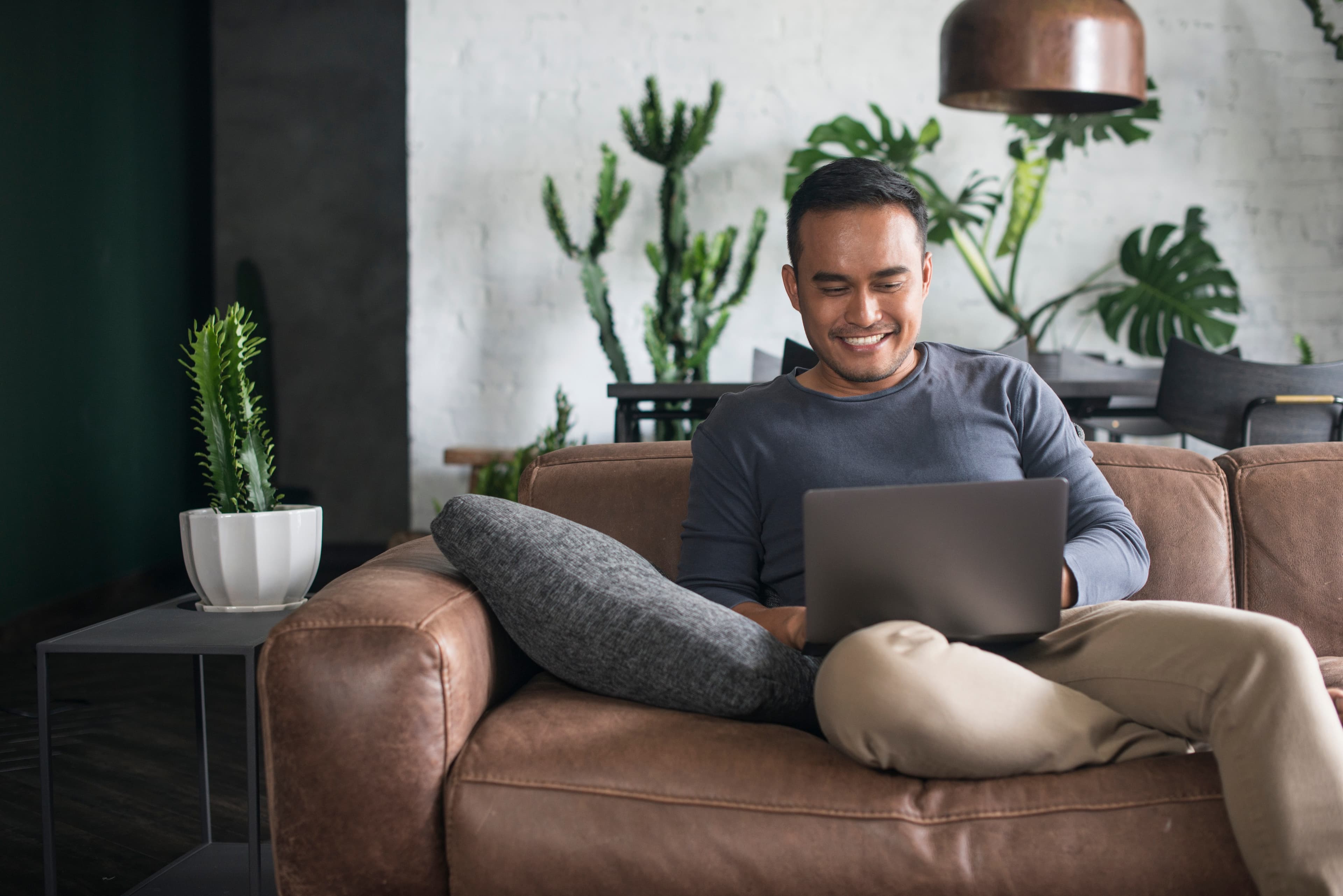 Man relaxing on couch with laptop browsing home listings